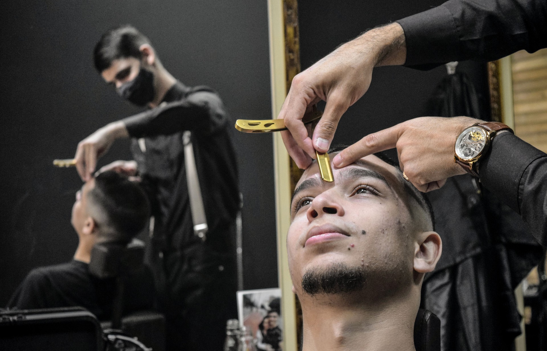 Young man at a barber shop, grooming his eyebrows